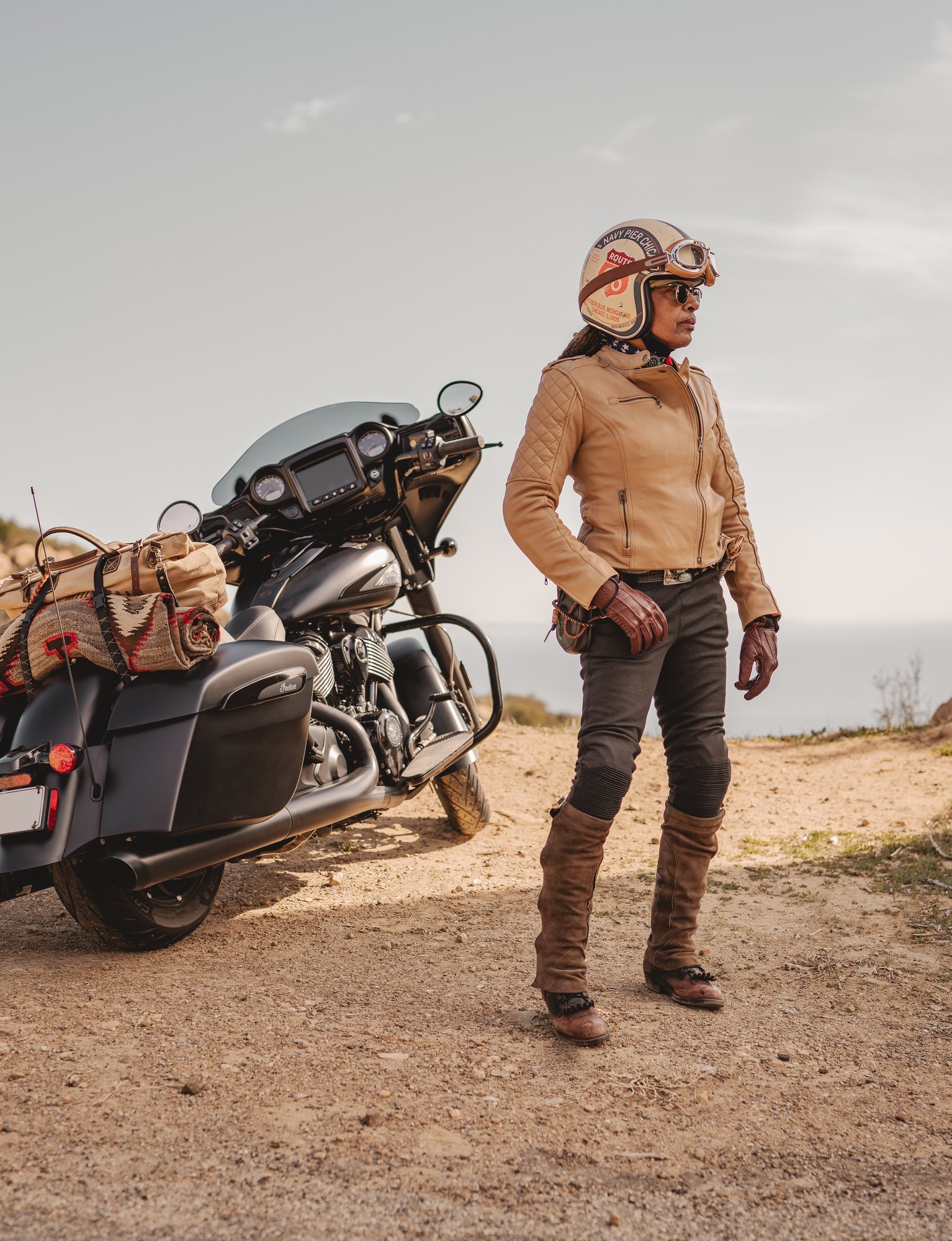 Gevin Fax standing beside her motorcycle on a coastal overlook